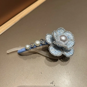 Detail of blue tweed camellia hair clip with pearl center and rhinestone accents