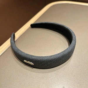 Macro shot of gray twill fabric headband with a gold handmade engraved metal label