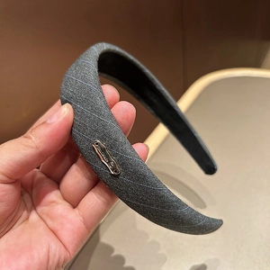 Detail of grey striped fabric headband with silver metal brand tag and non-slip lining