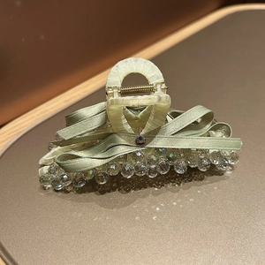 Close-up of a light green silk bow hair claw clip with crystal bead detailing
