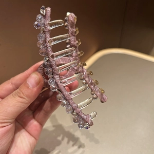 Detail of a large hair claw clip featuring pink satin ribbon and sparkling crystal beads