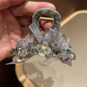 Detail of grey organza bow hair claw with crystal beads and a floral center ornament