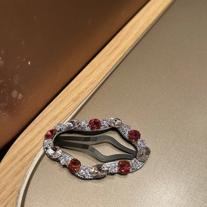Detail of wavy oval rhinestone hair clip with red and champagne crystals on silver base