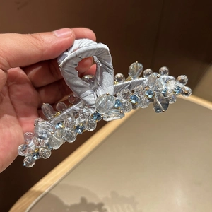 Dettaglio di un grande fermaglio per capelli con cristalli azzurri e nastro di raso grigio