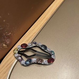 Macro shot of silver snap clip with colorful rhinestones on a warm gold background