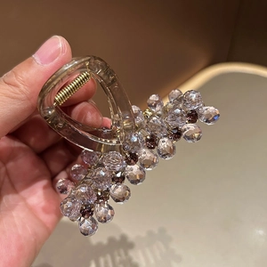Vue détaillée de la pince à cheveux en cristal avec perles mauves et ressort en métal doré