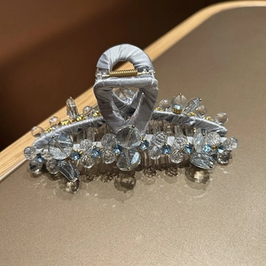 Dettaglio dell'elegante pinza per capelli in raso con cristalli blu e molla in oro fine
