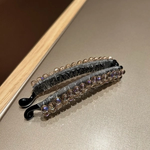 Close-up of crystal banana hair clip with champagne beads and grey fabric wrapping