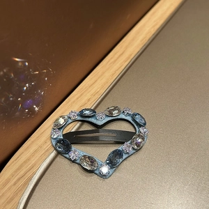 Detail of heart-shaped blue rhinestone hair clip with sparkling crystal embellishments