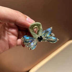 Detailed macro of crystal butterfly hair claw clip with emerald stone and silk handle