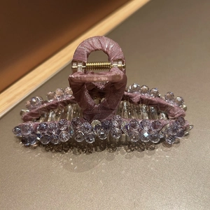 Detailed view of handmade pink crystal hair claw clip with purple rhinestones on gold surface