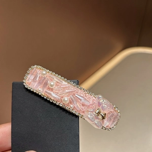Nahaufnahme der rosa Haarspange mit Kristallen, Perlen und kleinem Bären-Anhänger