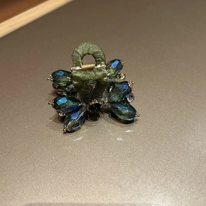 Close-up of vintage mini hair clip with emerald green satin and teal gradient crystals