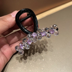 Close-up of elegant hair claw clip with lavender crystal beads and black glossy finish