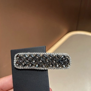 Detail einer rechteckigen Haarspange mit grauen und schwarzen facettierten Strasssteinen