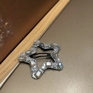 Close-up of star-shaped hair clip with sparkling rhinestones and black metal duckbill clip
