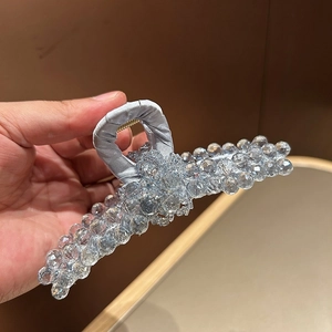 Dettaglio di un grande fermaglio per capelli con perle di cristallo e manico in raso