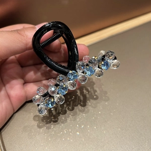 Detail of beaded hair claw clip with blue and clear crystals on black base