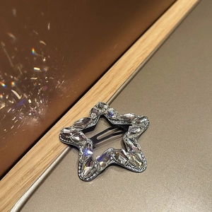 Close-up of star-shaped hair clip featuring sparkling rhinestones on a black metal base