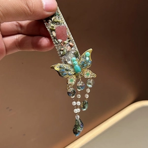 Detail of butterfly hair clip featuring green glitter stones and delicate beaded tassels