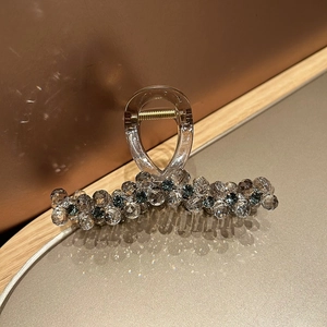 Close-up of luxury crystal shark hair claw with sparkling beads on a metal tray