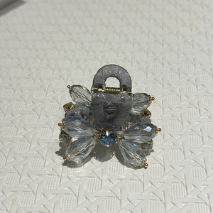 Detail view of handmade flower claw clip with blue crystals and grey mesh fabric wrap