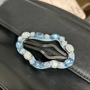 Detail view of cloud-shaped hair clip with light blue gems and rhinestones on black leather