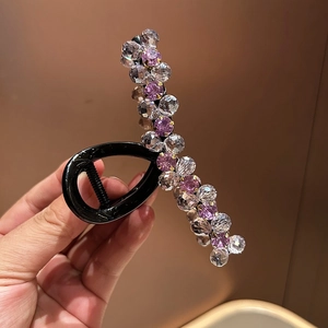 Close-up of purple and clear crystals on an elegant black hair claw clip