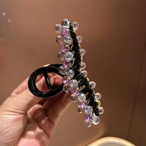 Close-up of crystal beaded claw clip showing purple faceted stones and spring mechanism