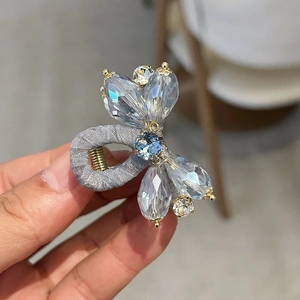 Detailed close-up of light blue and clear rhinestones on a gray fabric hair clip
