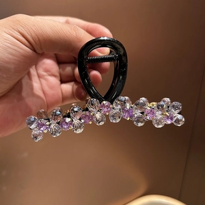 Detail of elegant hair claw clip with pink crystal beads and polished black finish