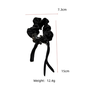 Detail showing elegant black satin scrunchie with long ribbons and clear crystal beads