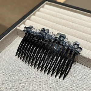 Macro view of a handmade crystal hair comb with blue beads on a beige jewelry tray