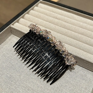 Detailed close-up of champagne crystal beads on a black hair comb accessory