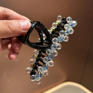 Macro detail of elegant hair claw clip featuring sparkling light blue crystal beads