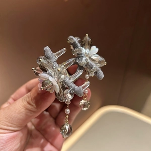 Détail d'un chouchou en cristal avec pierres grises, fleurs blanches et breloques