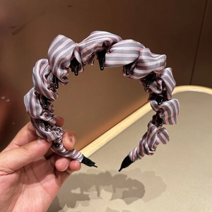 Dettaglio cerchietto in tessuto a righe rosa e grigie con denti antiscivolo in plastica nera