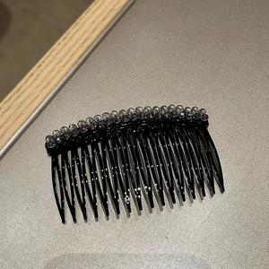 Dettaglio di un pettine per capelli nero a 17 denti con fiori in cristallo blu-grigio