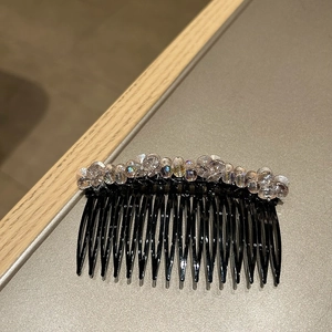 Detailed view of handmade hair comb with iridescent crystal beads on black plastic base