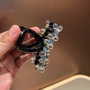 Detailed macro view of faceted crystal beads and blue gems on a black shark hair claw clip