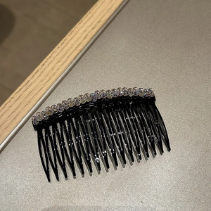 Dettaglio di un pettine per capelli nero con due file di strass di cristallo lucenti
