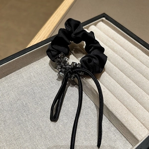 Close-up of elegant black satin scrunchie with sparkling rhinestones and long ribbons