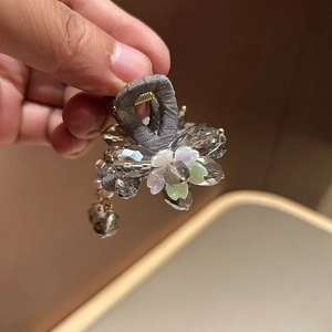 Vue détaillée de la mini pince à cheveux avec cristaux gris et pompon fleur nacré