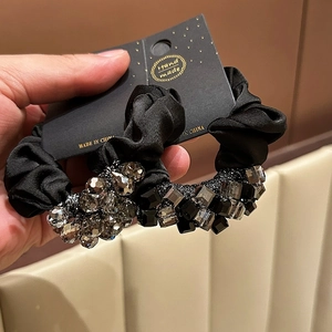 Detail of two black satin scrunchies with crystal beads on a handmade display card