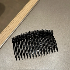 Dettaglio di un pettine per capelli nero con perle di cristallo per stili eleganti