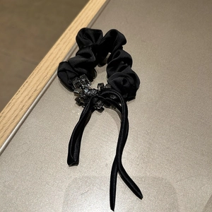 Detailed view of elegant black satin scrunchie with rhinestones and long streamers