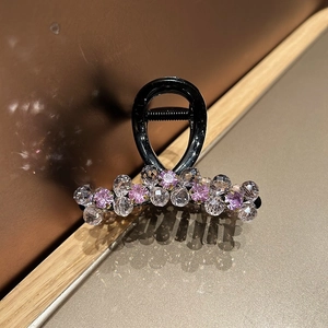 Close-up of elegant hair claw clip with pink and clear crystal beads on a metallic stand