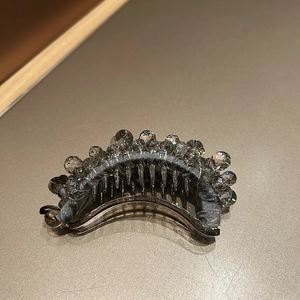 Detailed macro view of smokey grey crystal beads on a curved banana hair clip with teeth