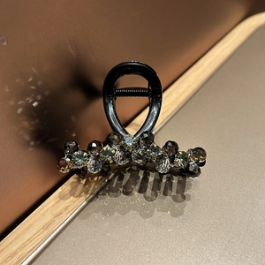 Close-up of elegant hair claw clip featuring shimmering dark crystal beads and glossy finish