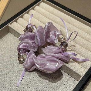 Eleganter lila Organza-Haargummi mit Schleife und Kristallperlen auf beige Schmuckdisplay